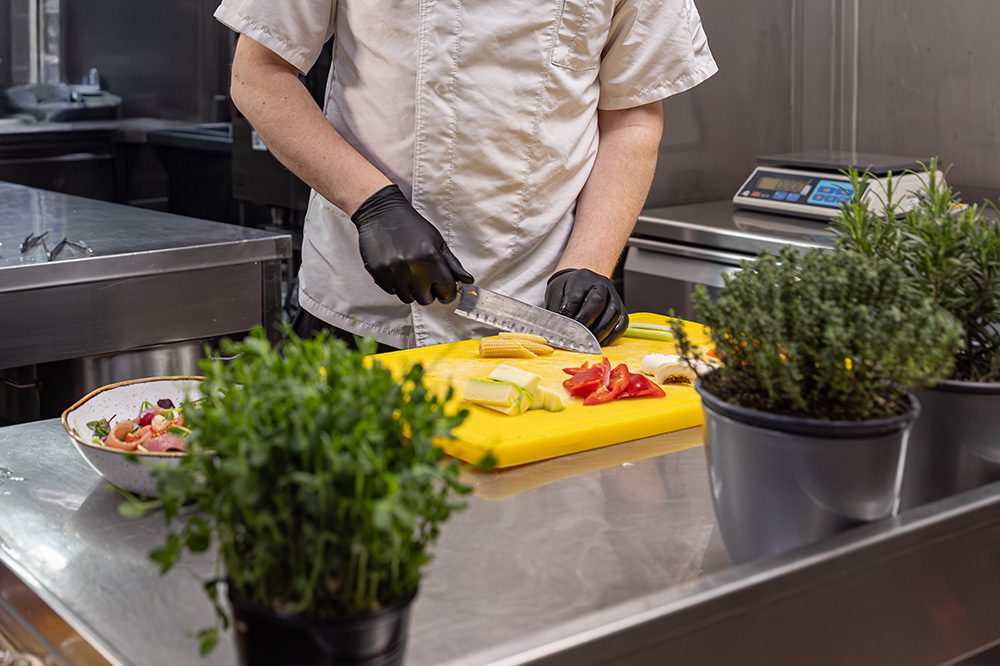 Chef chopping vegetables on stainless steel surface supported by Hoshizaki worktop refrigeration for prep and cold storage in one.