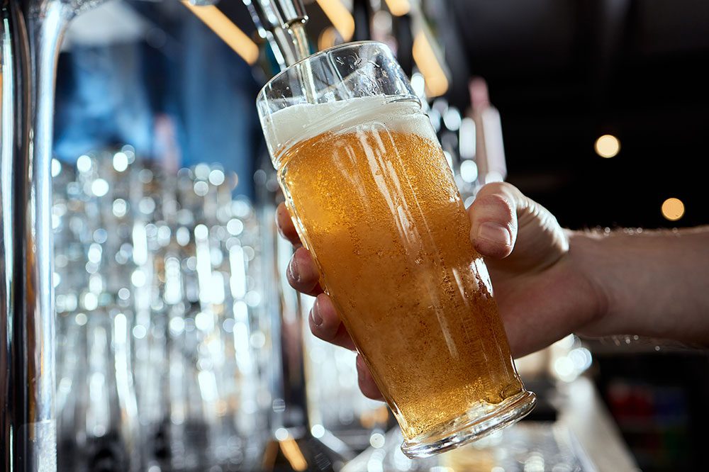 Bartender pouring a draft beer into a glass from Hoshizaki direct draw refrigerator, showcasing chilled tap service.