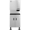 Stainless steel commercial ice and water dispenser with push-button controls, storage cabinet below, and black drip tray on the front.