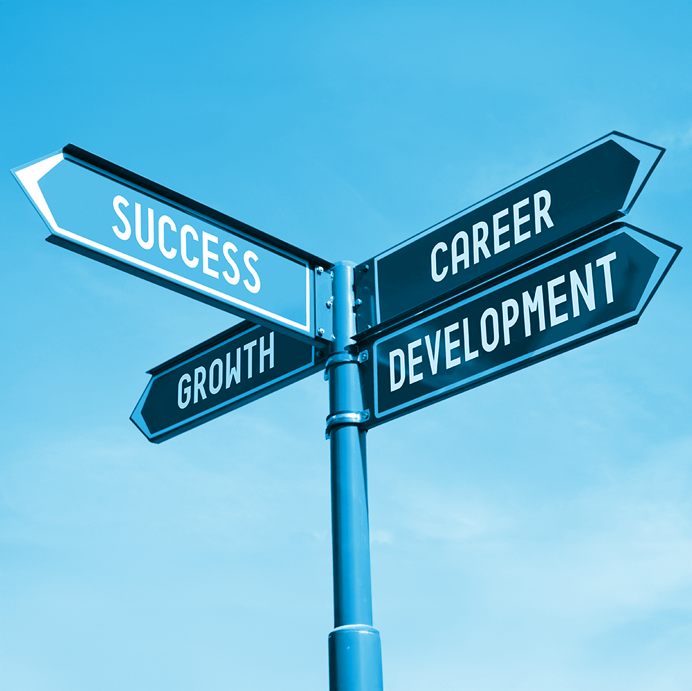 A street signpost with four arrows labeled Success, Growth, Career, and Development against a clear blue sky.