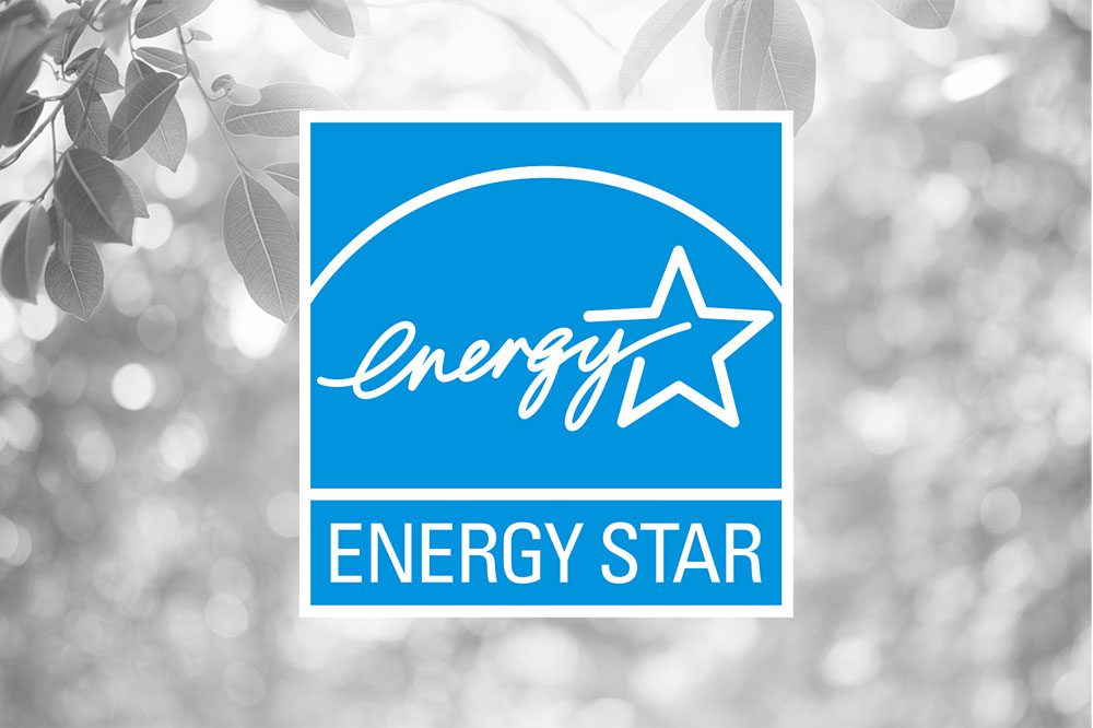 The ENERGY STAR logo displayed on a blue background, with stylized text and a star graphic; leaves and bokeh light in grayscale in the background.