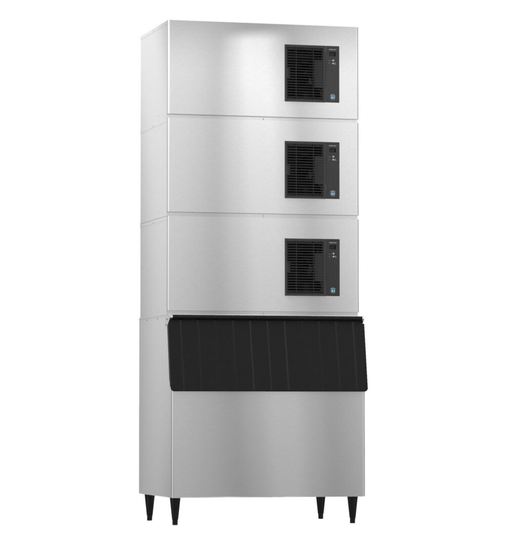 A large commercial ice machine with three stacked cooling units above a bin, all in a stainless steel finish, standing on four legs.