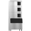 A large commercial ice machine with three stacked cooling units above a bin, all in a stainless steel finish, standing on four legs.