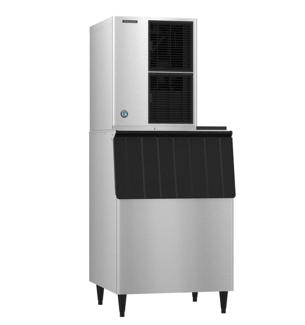 A commercial stainless steel ice machine with a top ice maker unit and a bottom storage bin, standing on four legs.